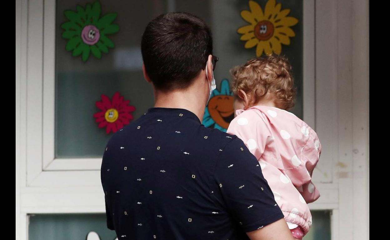 Un padre con su hija a la puesta de una guardería.. 