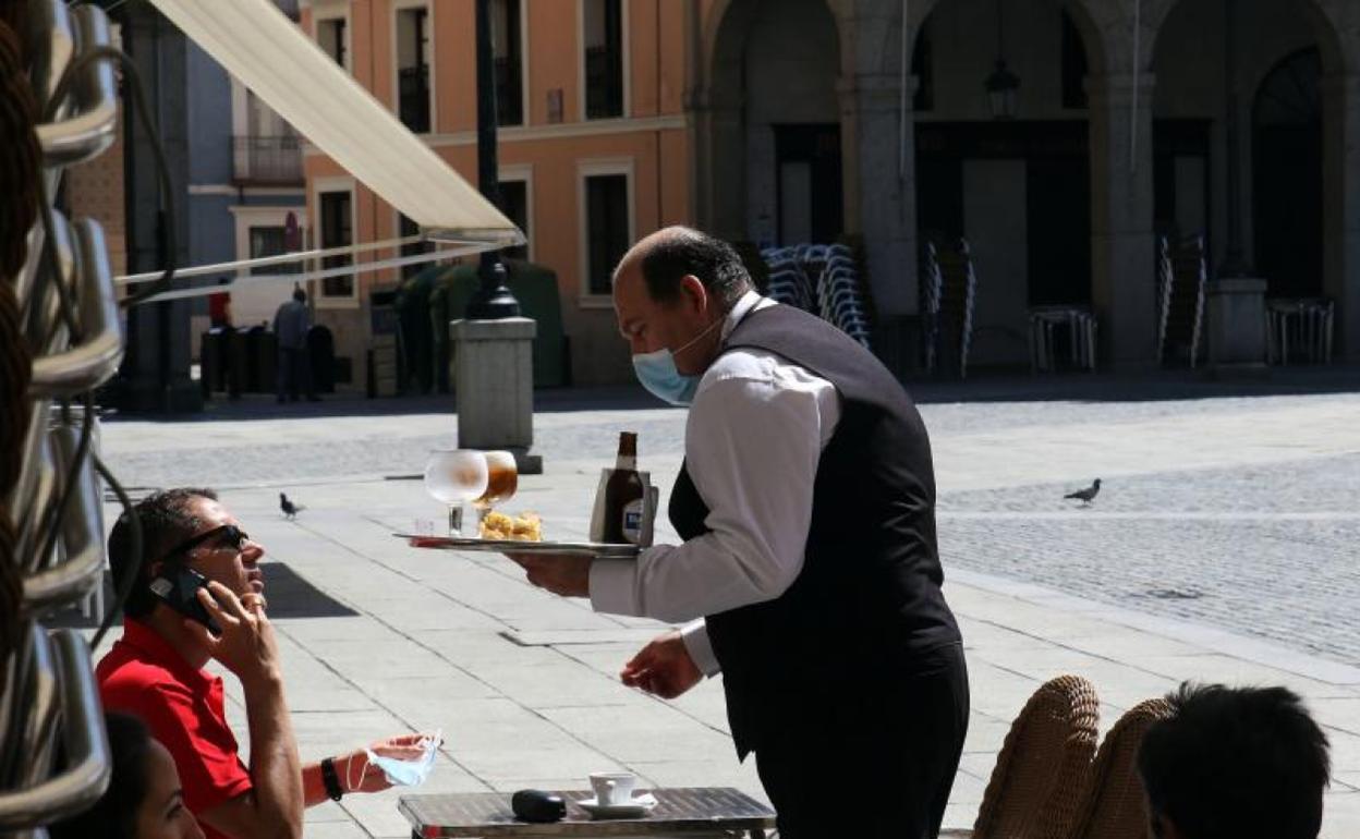 Un camarero sirve una mesa en una terraza de Segovia. 