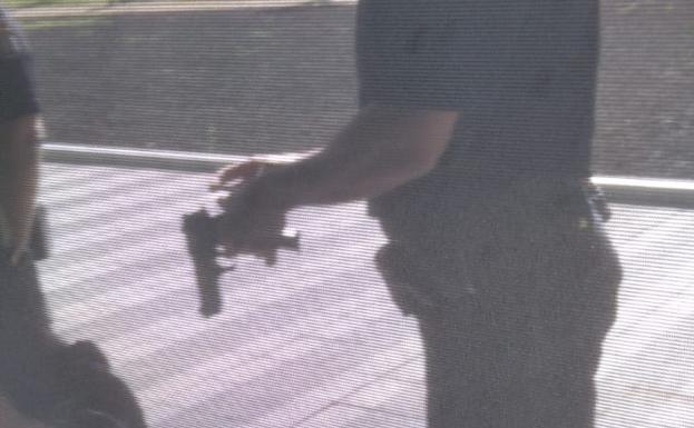 Un policía, con el arma de fogueo en su mano. 