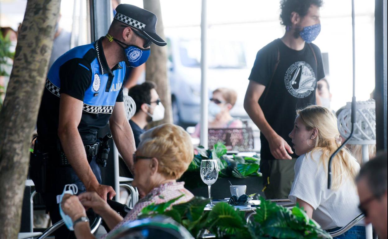 El agente Iván C. pide a una joven que se ponga la mascarilla tras beber su consumición en una terraza. 
