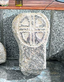 Imagen secundaria 2 - Arriba, una de las obras de 'land art' en El Collao; portada de la iglesia luce un escudo con conchas de peregrino y estela funeraria del siglo XIV que fue encontrada en la iglesia en 2013. .