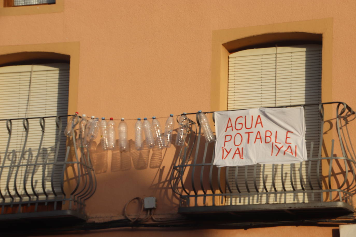 Balccones con botellas de agua vacías y pancartas reivindicativas en Lastras de Cuéllat. 
