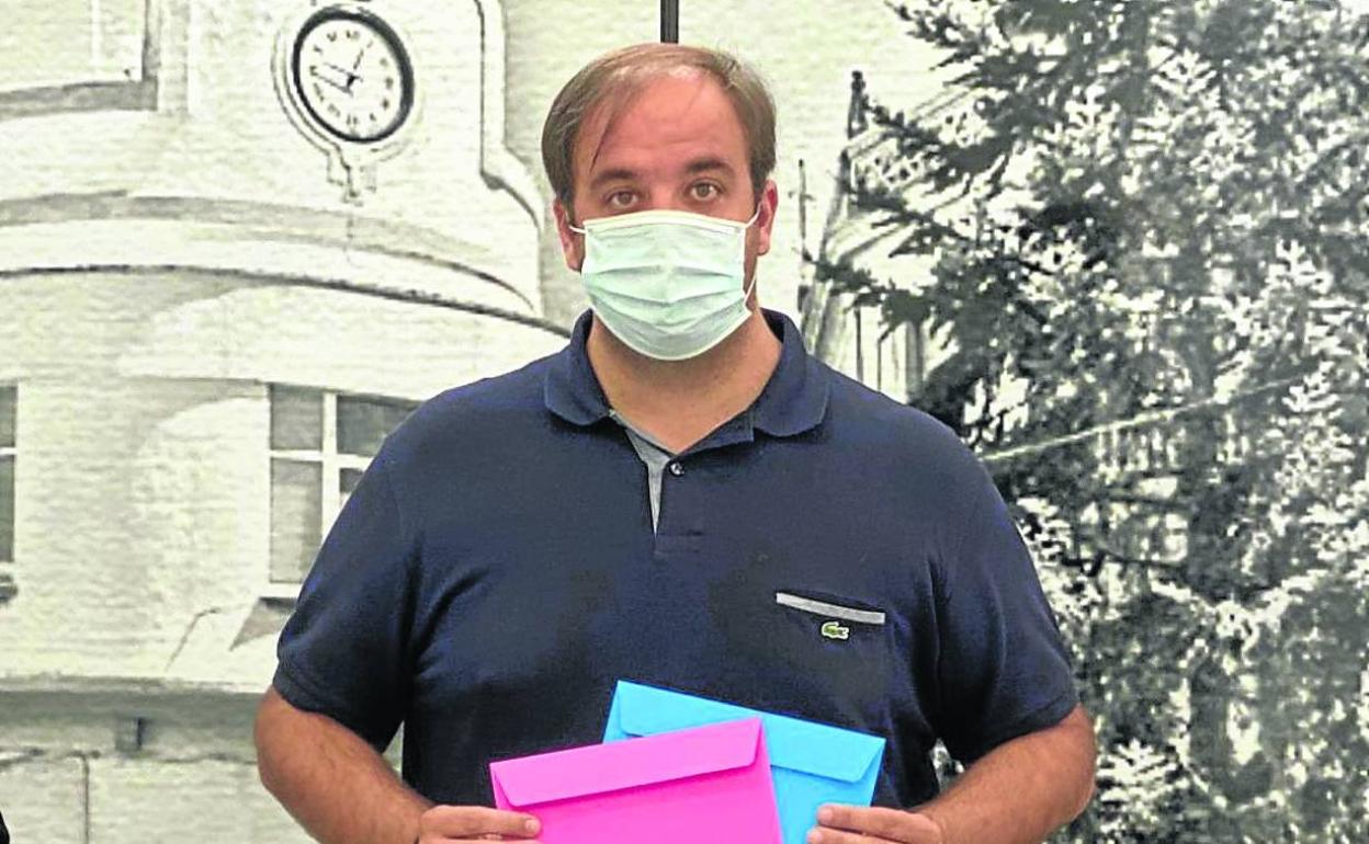 El alcalde Roberto Martín sostiene en sus manos unos cheques-bebé para los vecinos.