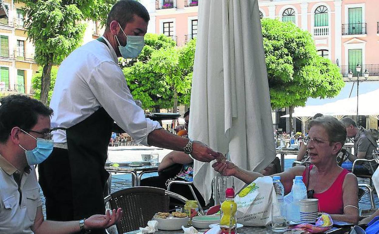 Un camarero atiende una mesa en una terraza de Segovia. 