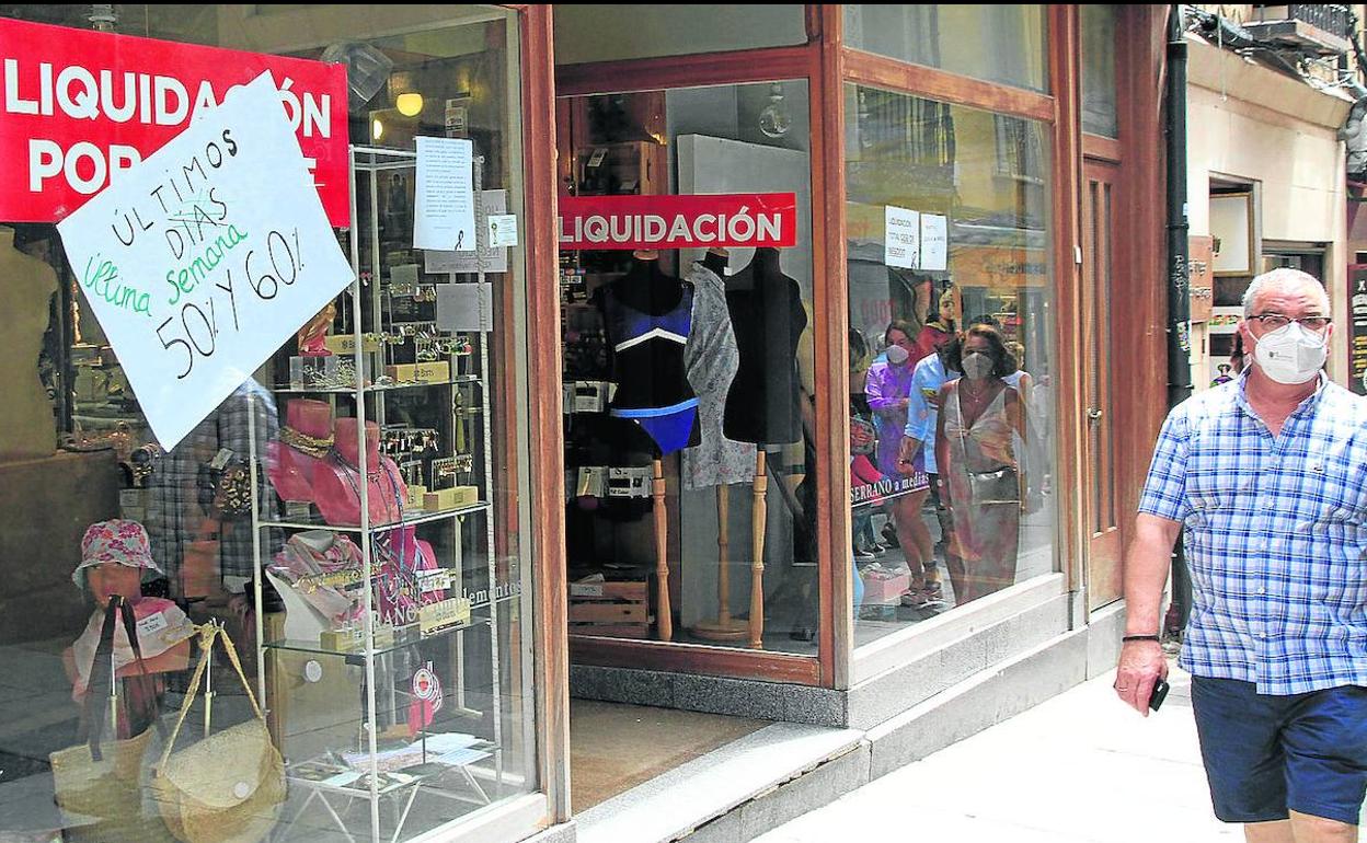 Un hombre camina junto a un comercio de la Calle Real que anuncia su inminente cierre.