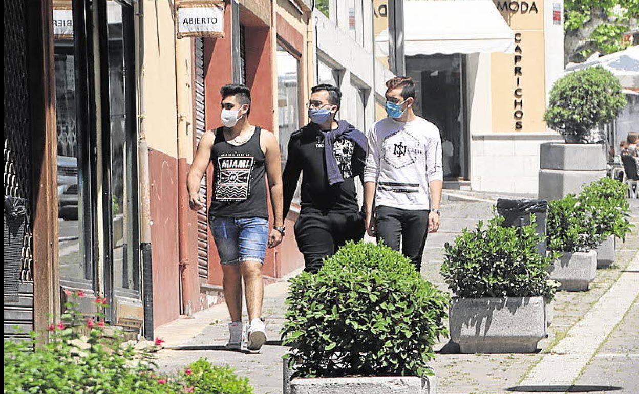 Tres jóvenes pasean provistos de sus mascarillas por una calle de Cuéllar. 