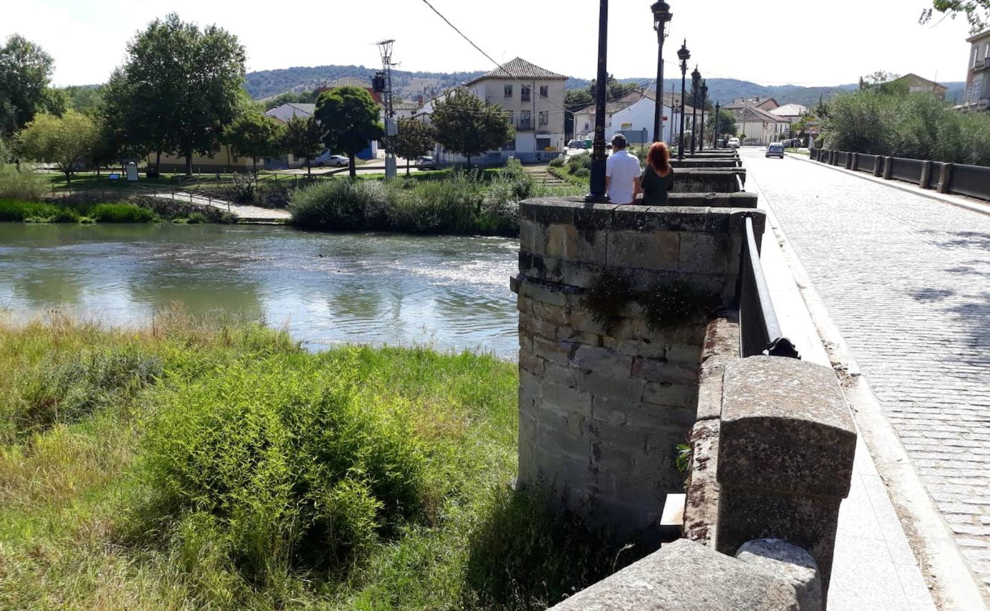 Dos personas observan ayer el Pisuerga desde el puente, otros años lleno de público.