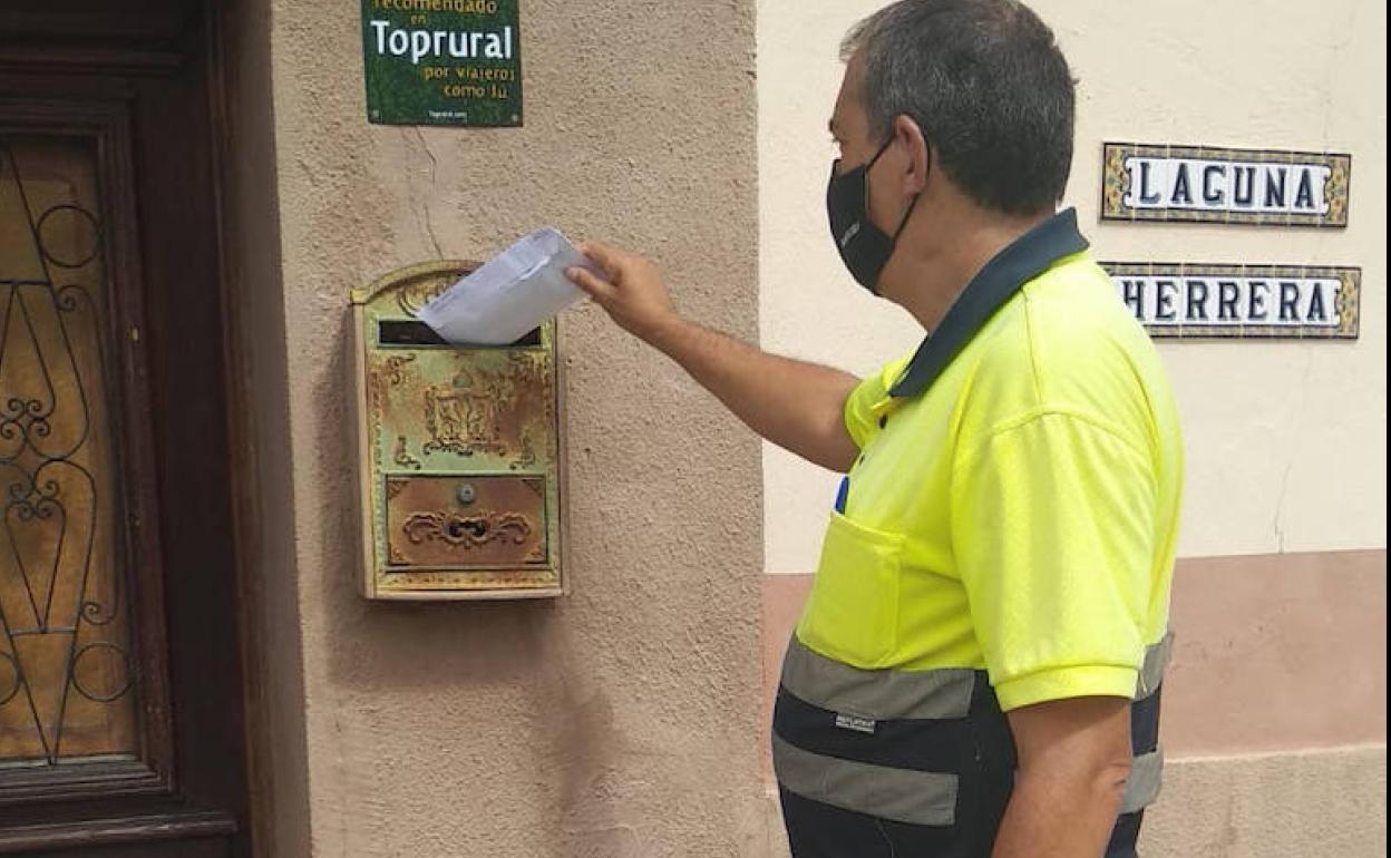 Un operario deja un sobre con mascarillas en un buzón de una vivienda de Campo de Cuéllar. 