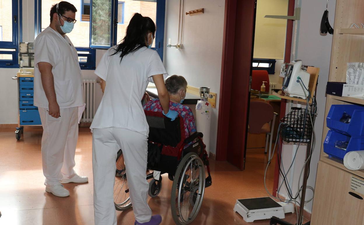 Dos enfermeros conducen a una mujer a realizarse una PCR. 