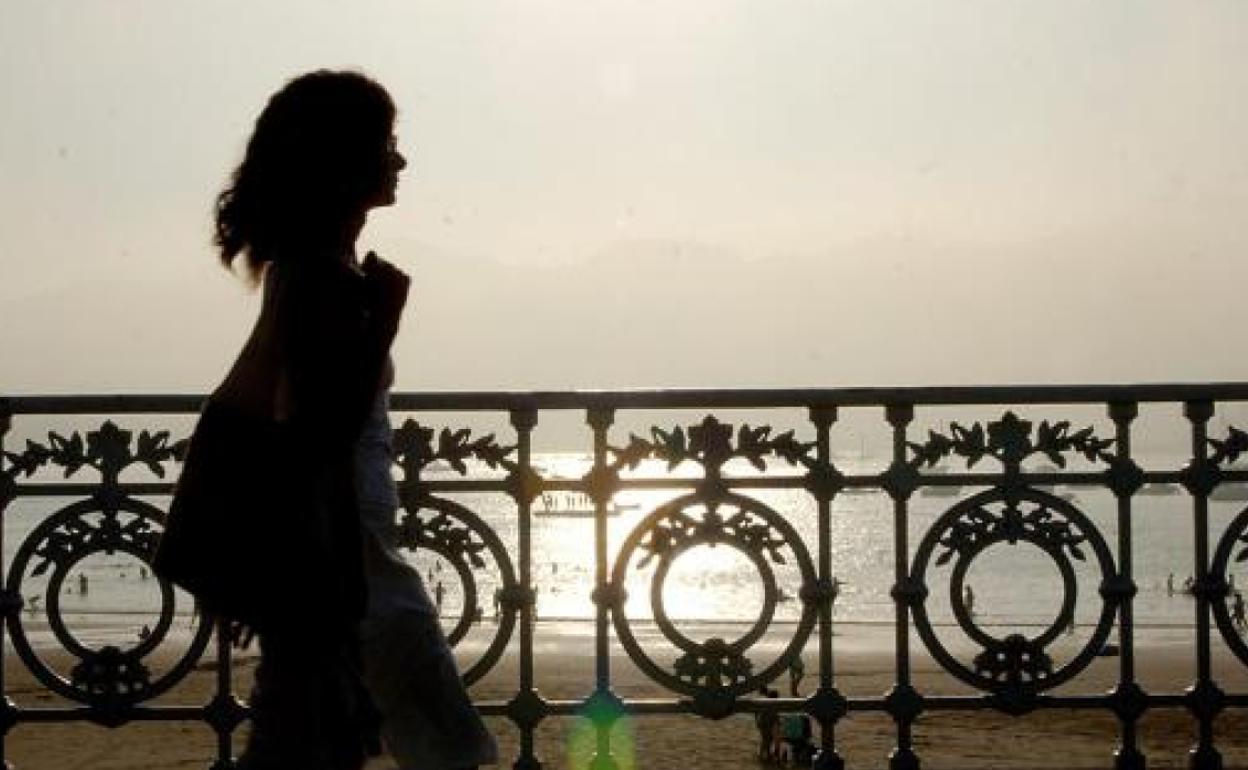 Joven pasea por la bahía de La Concha, en San Sebastián, durante una neblinosa tarde de verano. 