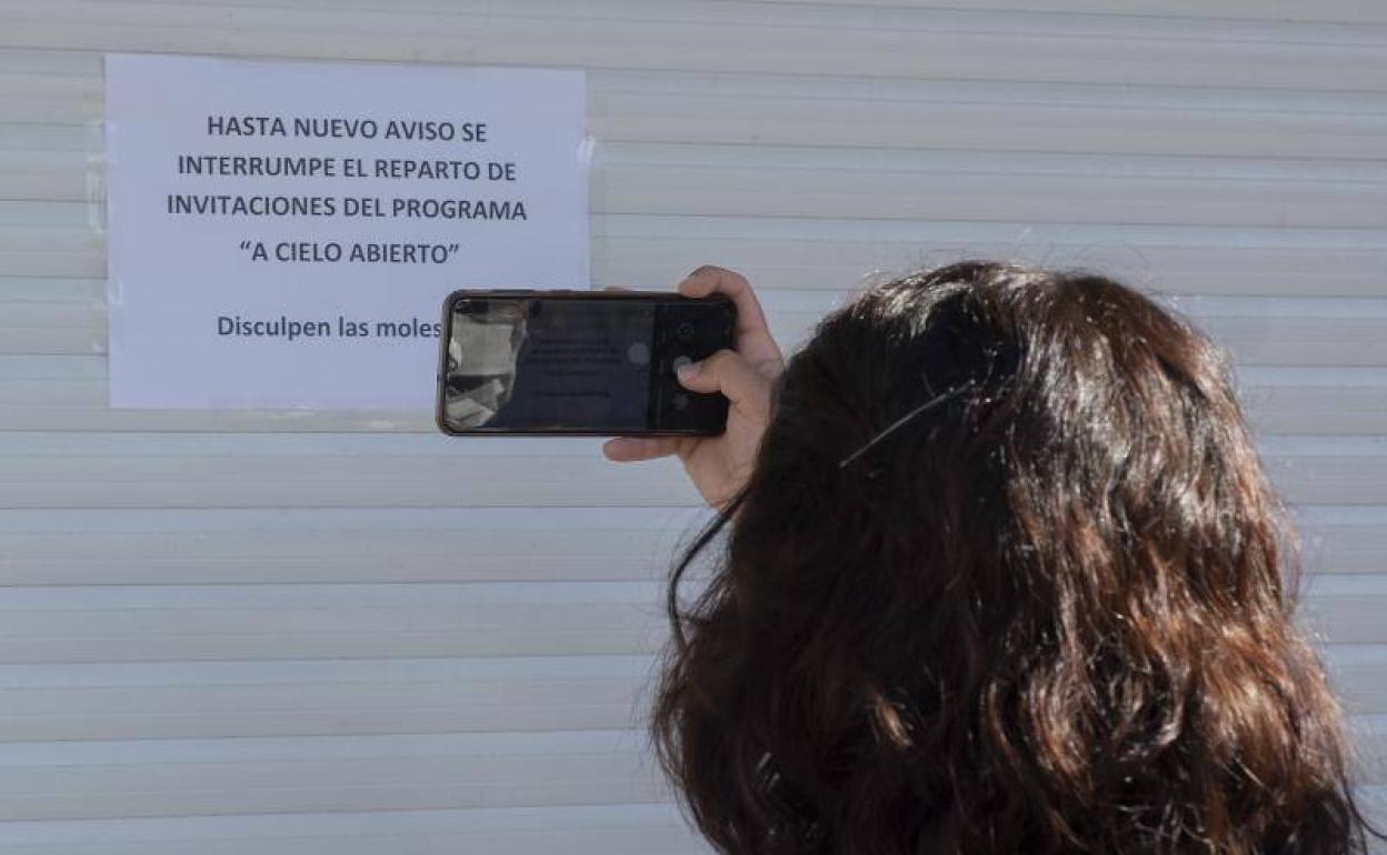 Una mujer fotografía el aviso en la caseta de reparto de entradas de 'A cielo abierto', en la plaza de Zorrilla. 