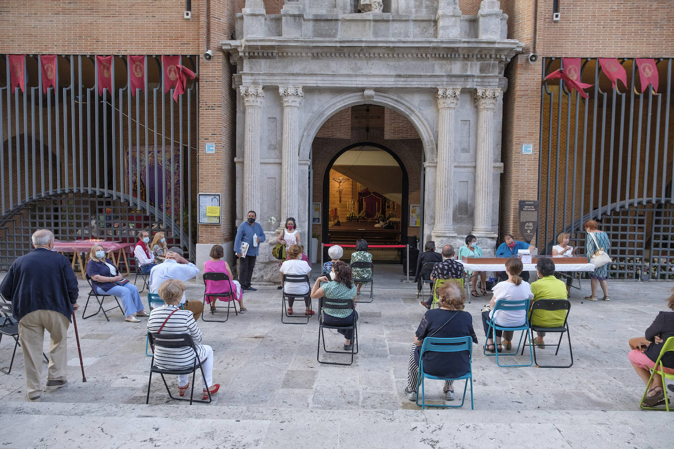 Hay sillas negras, azules y verdes, esparcidas por el empedrado suelo del acceso a la iglesia de San Lorenzo, en la calle Pedro Niño | Y allí, sentados, en la calle y con la vista en el interior del templo, un grupo de fieles sige la celebración