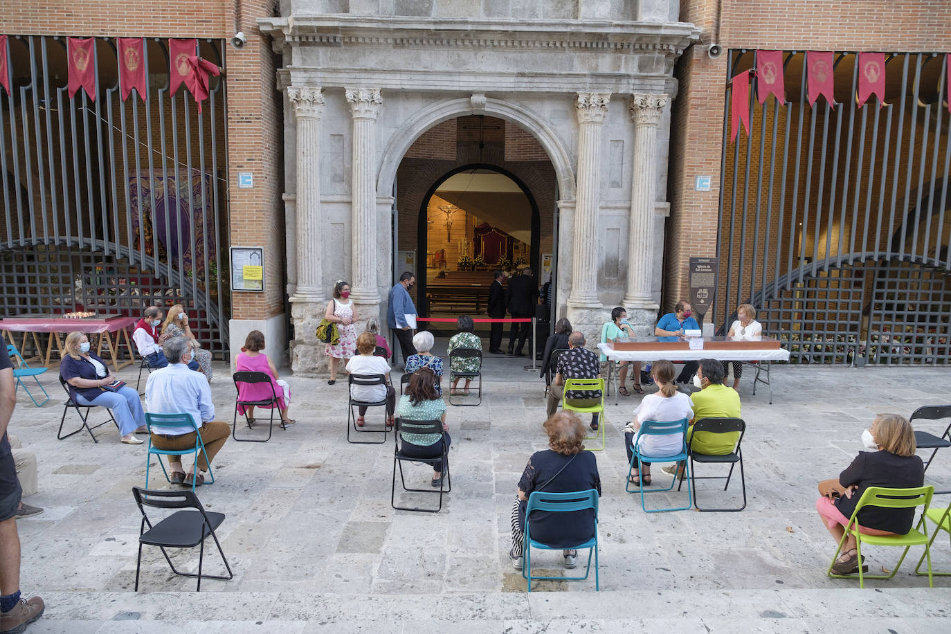 Hay sillas negras, azules y verdes, esparcidas por el empedrado suelo del acceso a la iglesia de San Lorenzo, en la calle Pedro Niño | Y allí, sentados, en la calle y con la vista en el interior del templo, un grupo de fieles sige la celebración