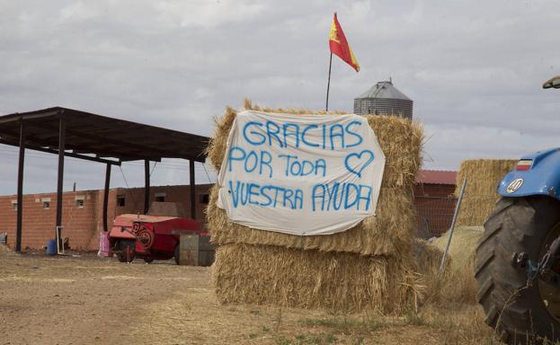 Imagen principal - Arriba, una pancarta de agradecimiento colocada a la entrada de la explotación de los hermanos Rey en Vegalatrave; en las imágenes de debajo, la alcaldesa de de Vegalatrave, María Isabel Álvarez, señala la zona quemada en la explotación ganadera de los hermanos Rey y Pascual Blanco, alcalde de Gallegos del Río, municipio al que pertenece Domez de Alba, señala por dónde llegaron las llamas desde Lober.