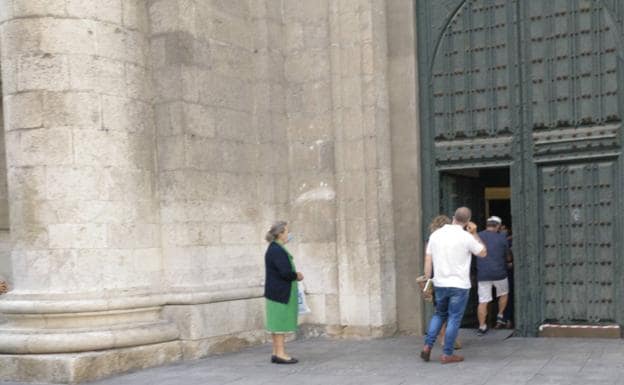 Varias personas acceden a la Catedral de Valladolid este domingo antes de la misa de las 18:00 horas, cuando se abrieron las puertas para dejar salir a dos visitantes. 