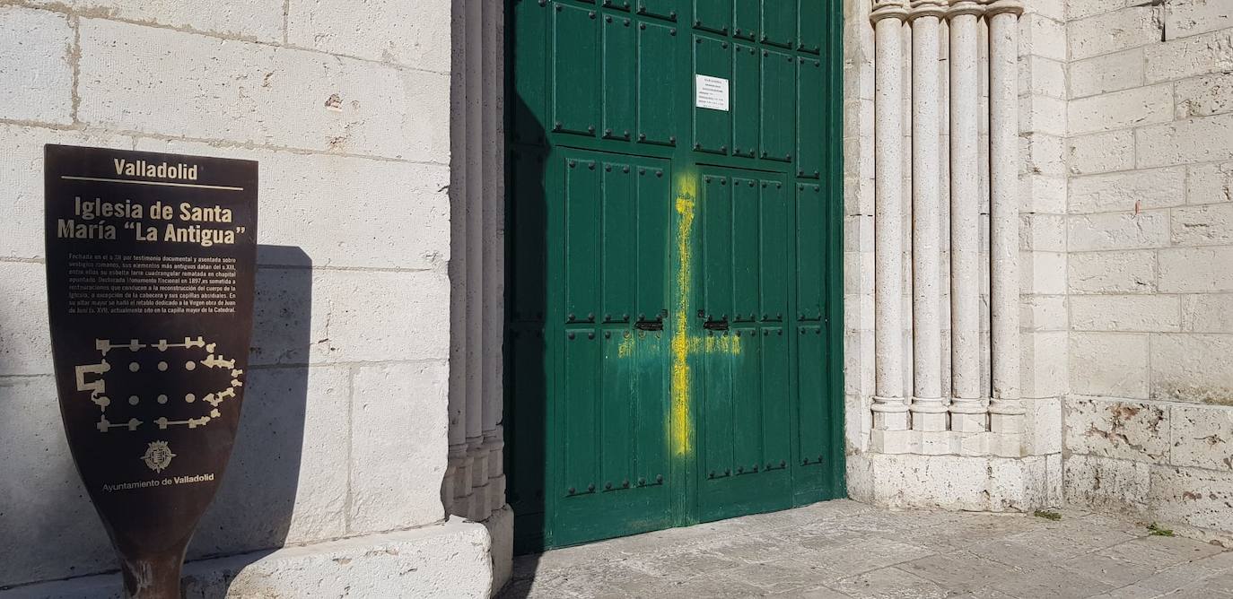Cruz invertida pintada en amarillo en la puerta de la iglesia. 