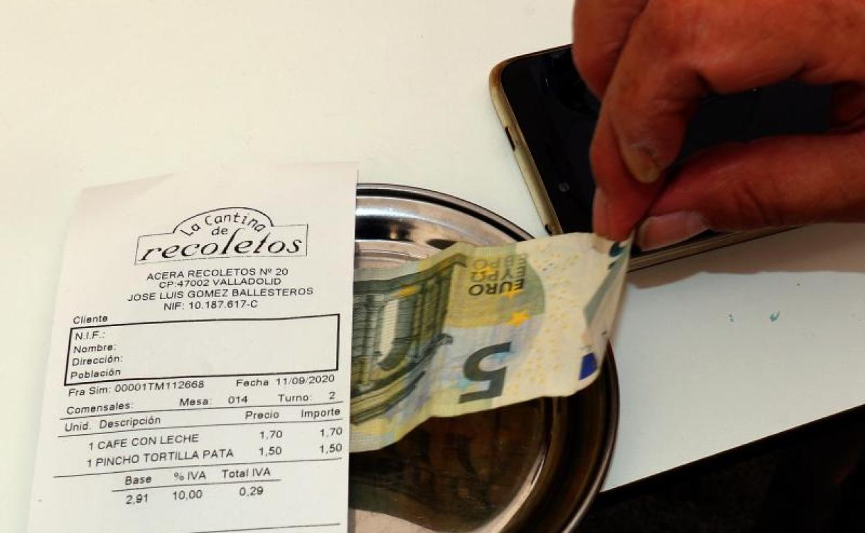 Una persona abona su consumición en una terraza, con su correspondiente IVA del 10%.