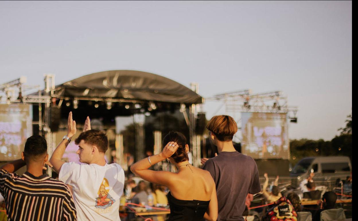 Estampa del Wild Field Festival, con el público en grupos de máximo de seis personas en torno a mesas y bancos de madera separados con cintas.