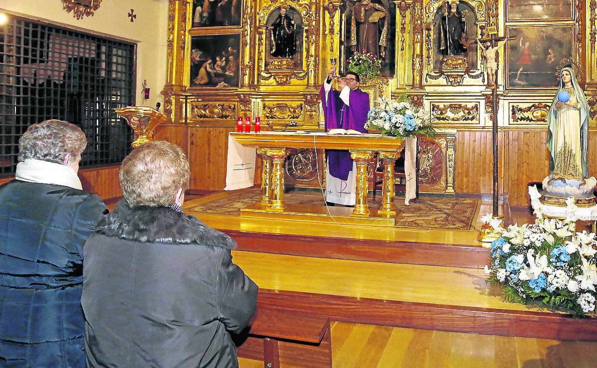 Dos señoras atienden al sacerdote durante una misa. 