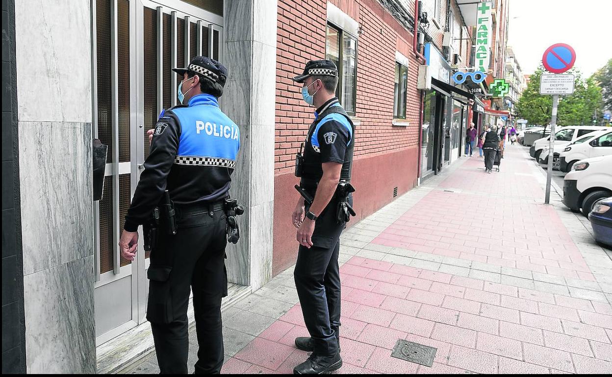 Dos agentes de la Policía Local de Valladolid, ante la puerta de un inmueble de la capital. 