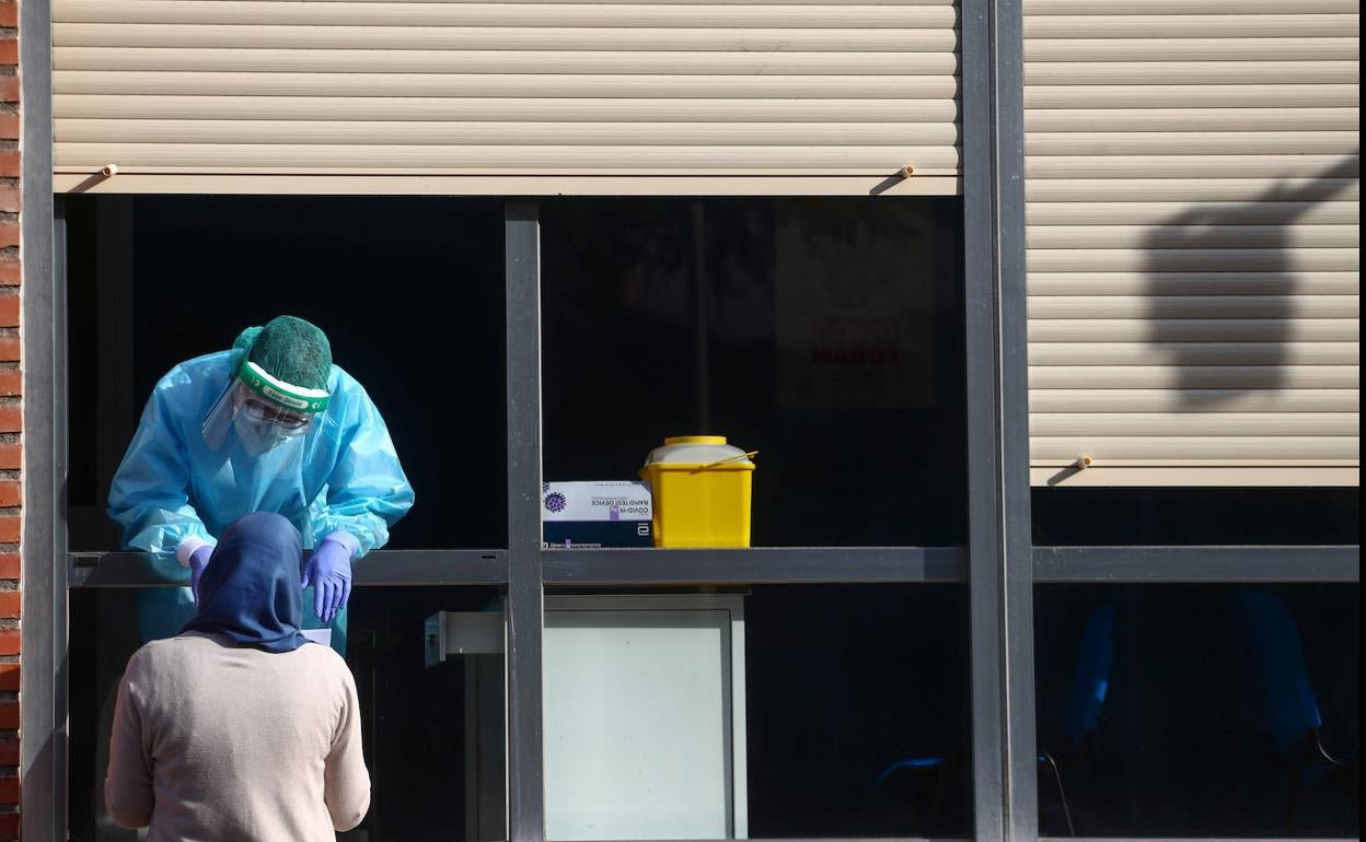 Personal sanitario entrega el resultado de una prueba de covid a una vecina de Orcasitas, al sur de Madrid.