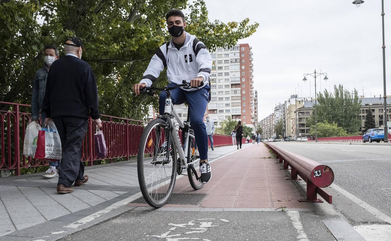 Un joven circula con su bicicleta por el canal para las dos ruedas del puente de Adolfo Suárez. 