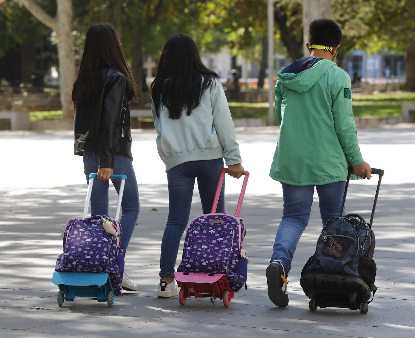 Tres estudiantes caminan por el parque del Salón. 