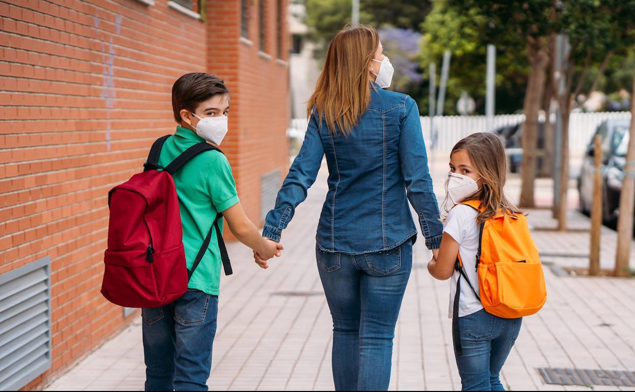 Una madre lleva a sus dos hijos al colegio.