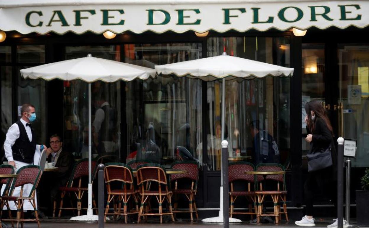 Un camarero atiende a los clientes en la terraza del Cafe de Flore parisino