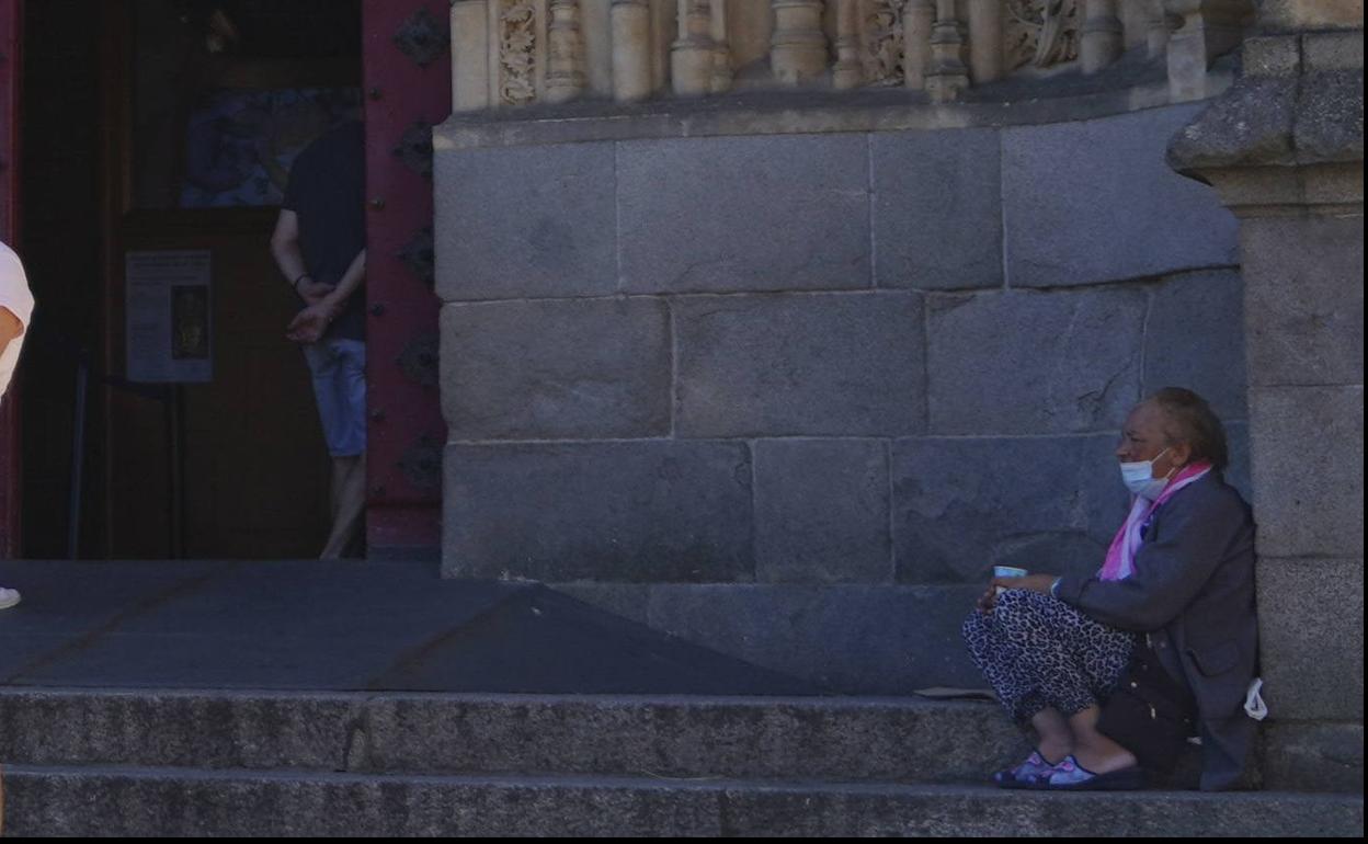 Una mujer pide dinero a la puerta de un templo.