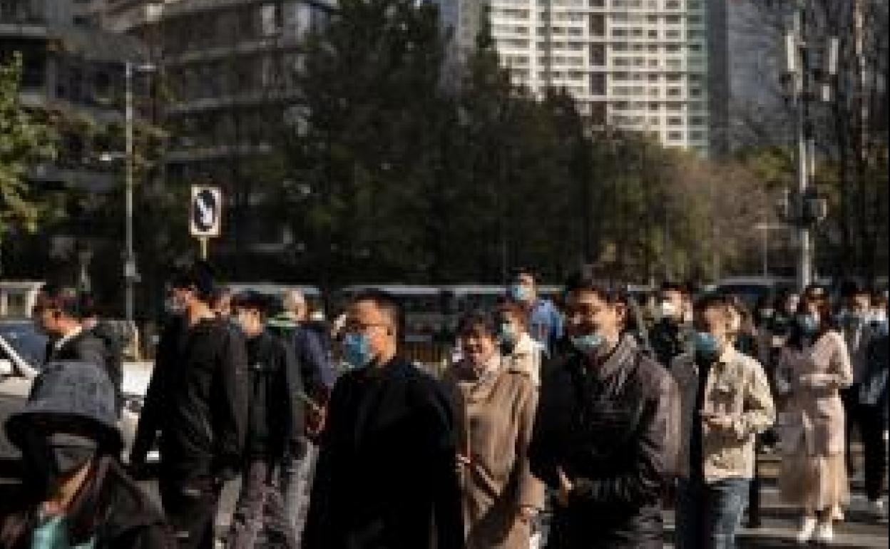 Vecinos de Pekín cruzan por una calle del distrito de negocios de la ciudad. 