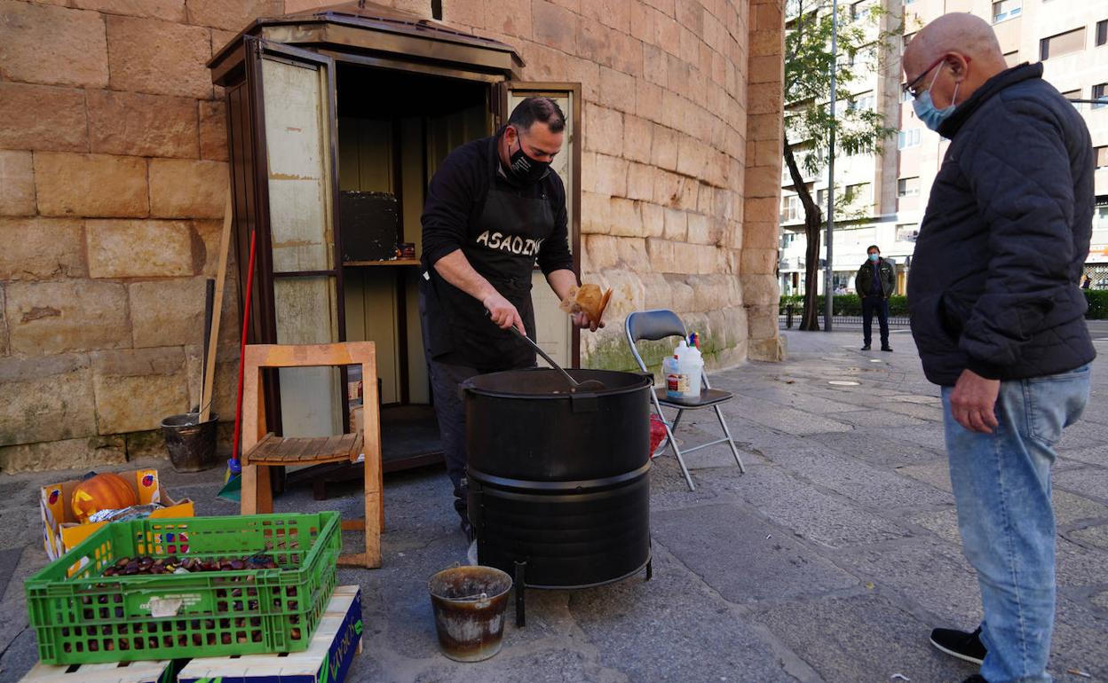 Miguel Ángel Hernández, atiende a un cliente en su puesto de castañas en Salamanca.