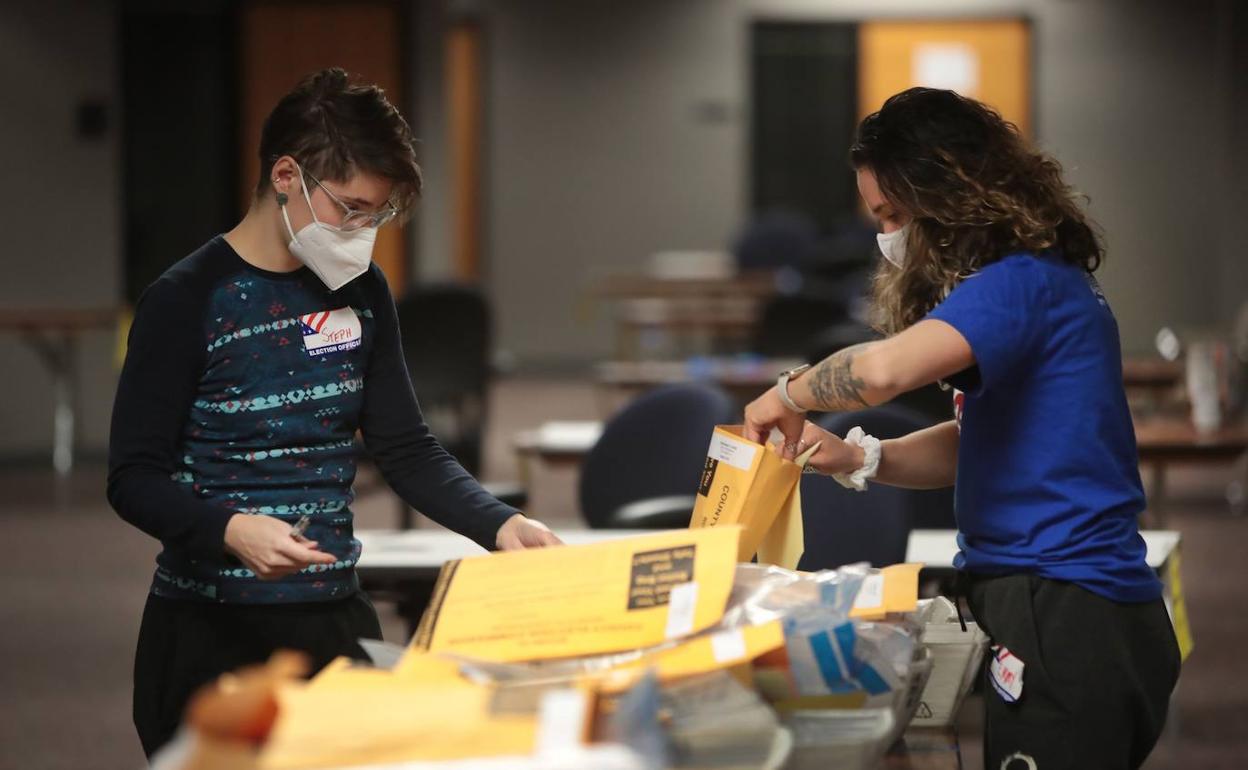 Dos voluntarias cuentan papeletas en un centro de votación de Wisconsin.