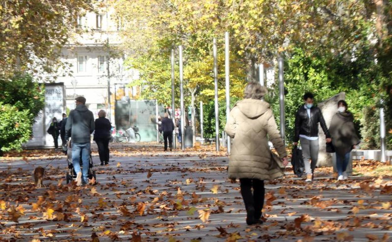 Los peatones caminan entre las hojas por la Acera de Recoletos.