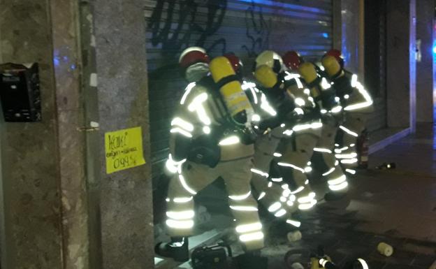 Los bomberos intentan abrir la puerta del local. 