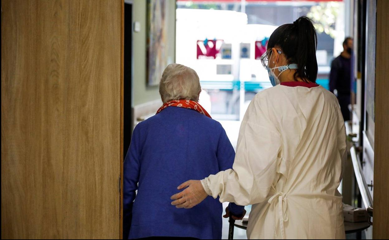 Una enfermera ayuda a una anciana en el hospital.