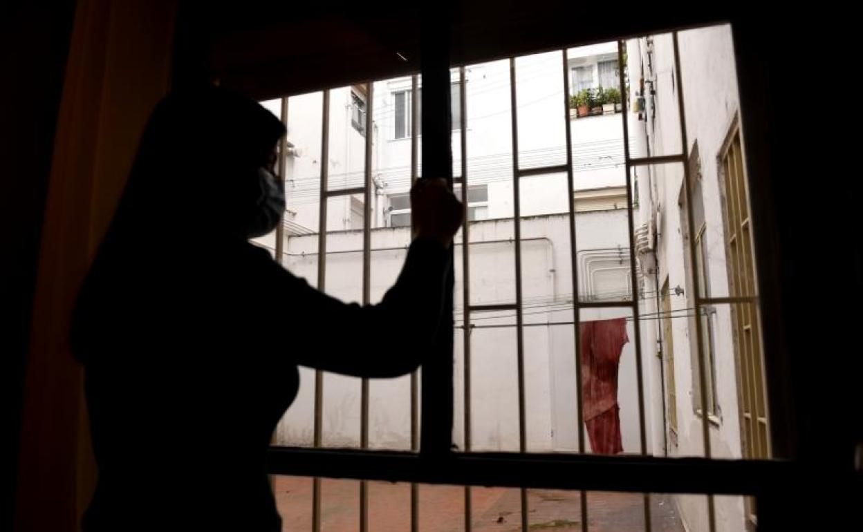 Una joven observa las vistas que le ofrece la ventana de su vivienda durante el confinamiento. 