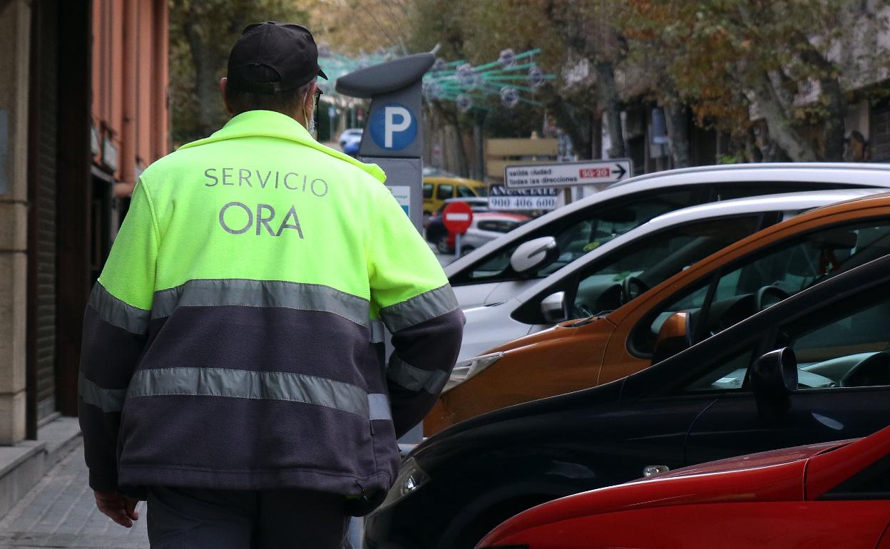 Un controlador de la ORA revisa varios vehículos estacionados en una calle de Segovia.