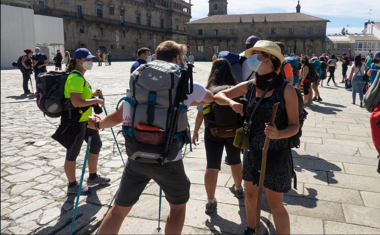 Dos peregrinos se saludan con el codo al llegar este verano a Santiago de Compostela.