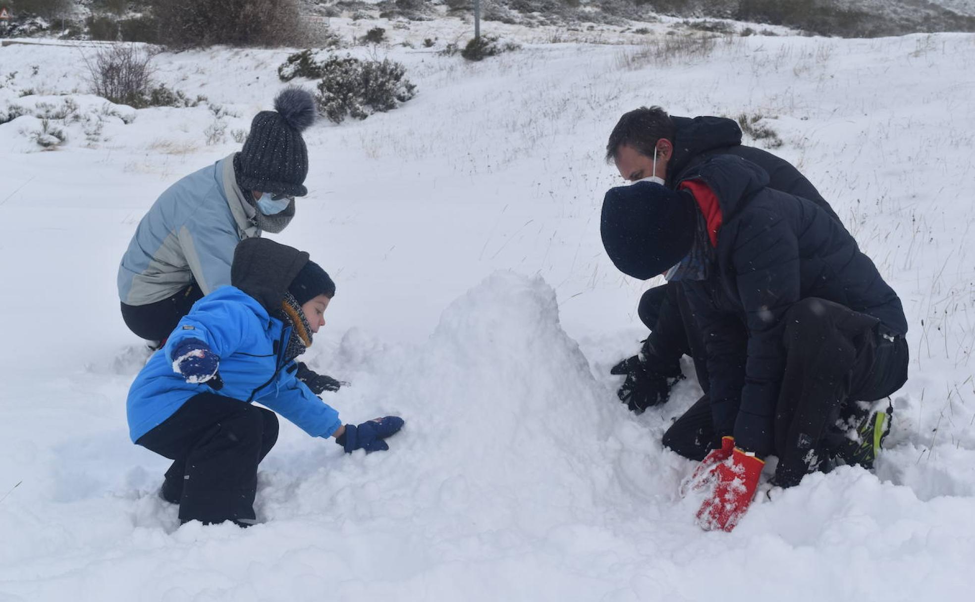 Una familia hace un muñeco de nieve, este domingo en Brañosera.