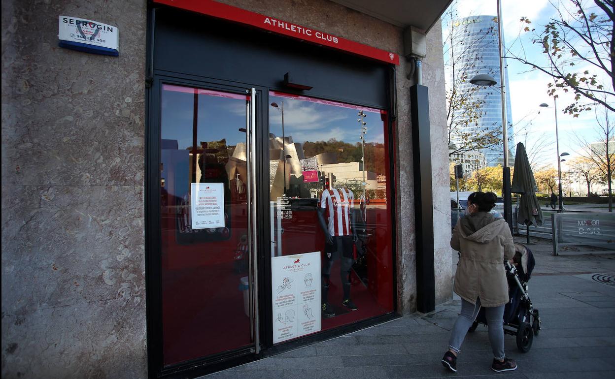 Una mujer camina frente a una tienda cerrada por las restricciones en Bilbao.