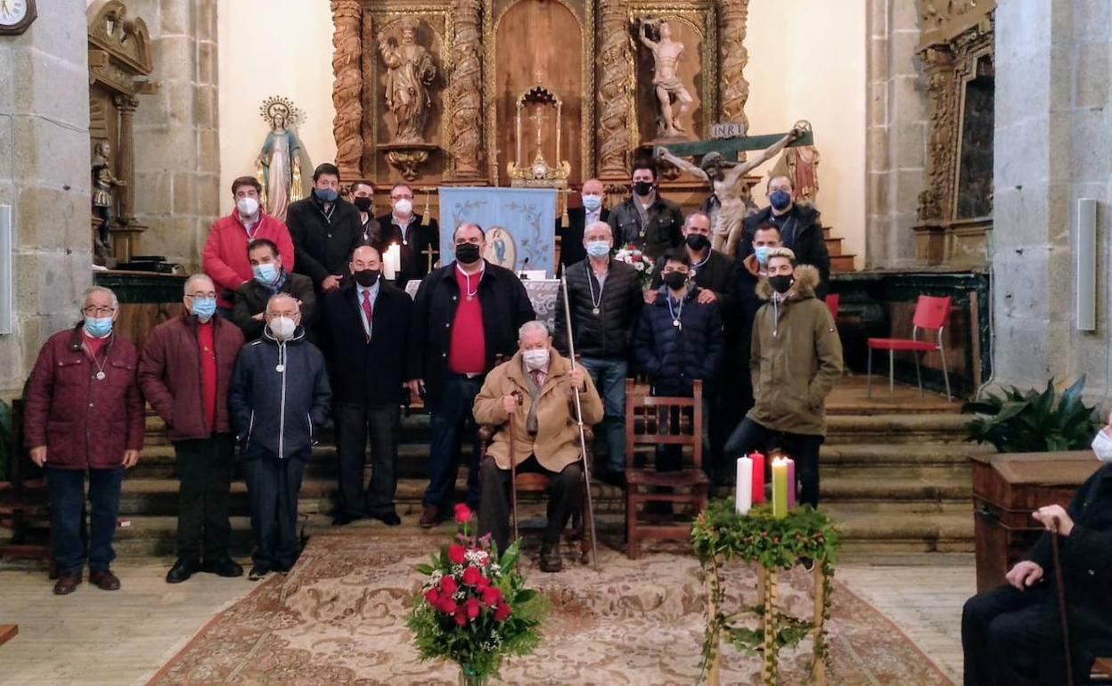 Los cofrades de la Inmaculada Concepción de Sequeros asistentes a la misa, con el abad a la derecha, sentado en un banco. 