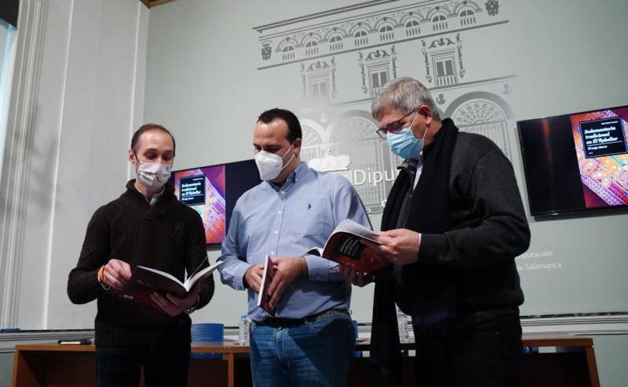 Raúl Benito, David Mingo y Francisco Blanco ojean el libro. 