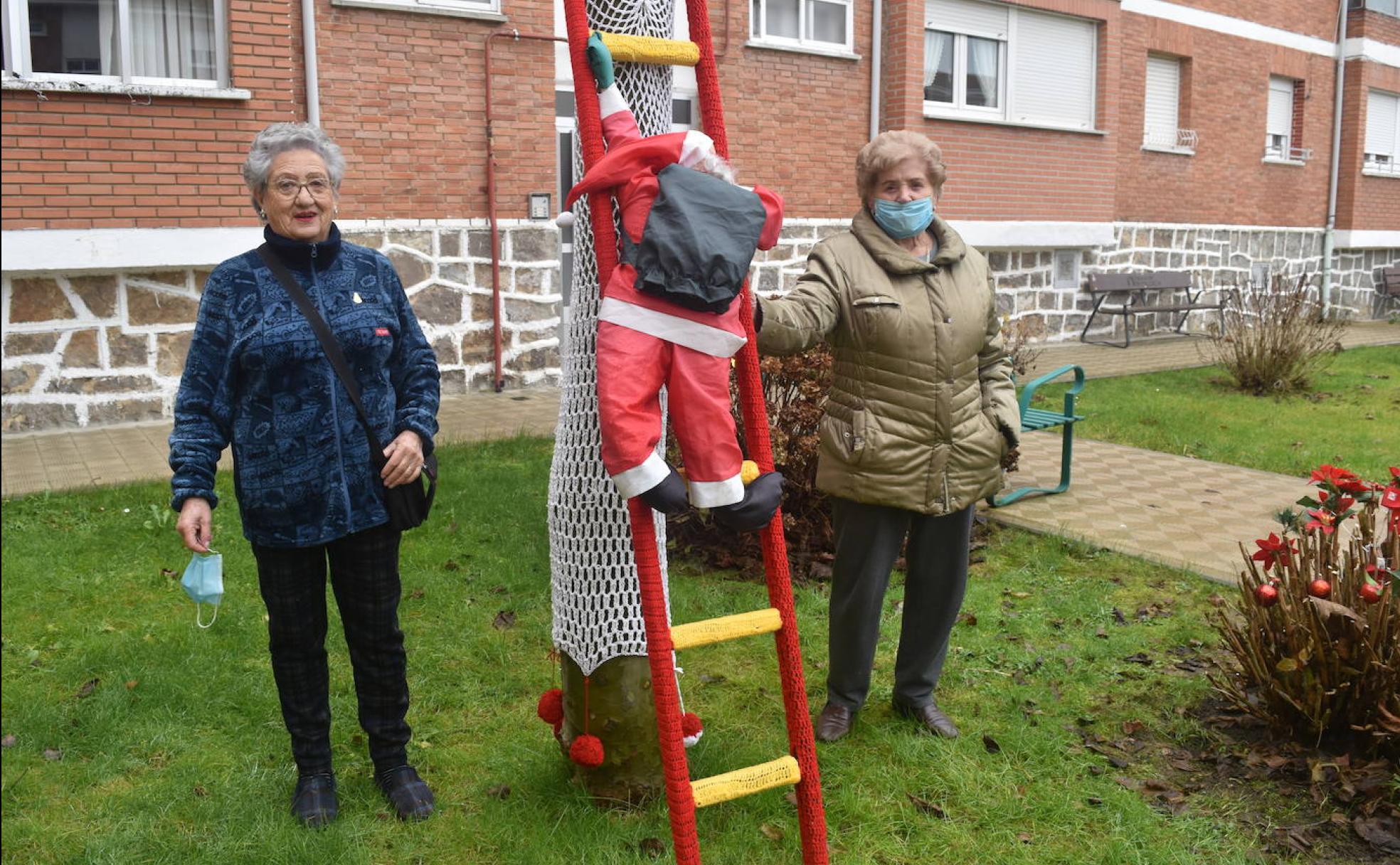 Carmina y Felisa, con una escalera por la que Papá Noel sube a uno de los árboles. 