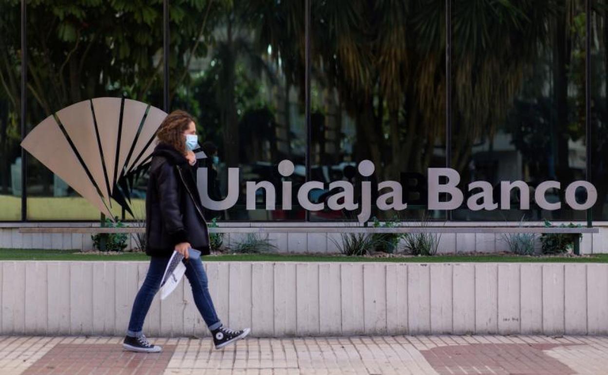 Una mujer pasa ante la sede de Unicaja en Málaga.