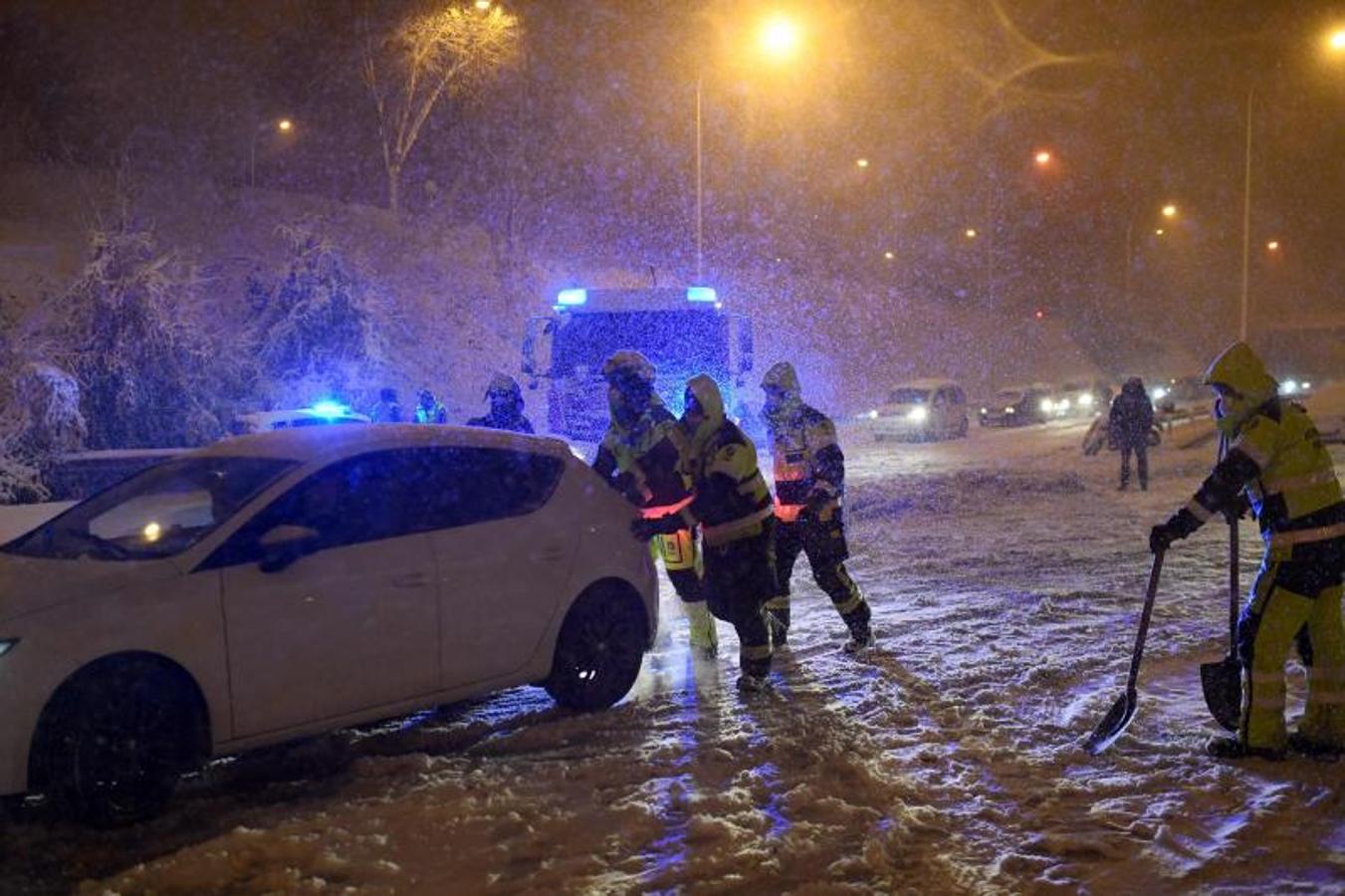 Los bomberos ayudan a los vehículos atascados en la carretera de circunvalación M30 en Madrid.