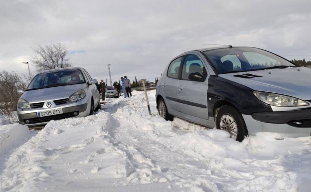 Imagen principal - Los vecinos intentan sacar los coches atrapados en la nieve en en el camino Palomares. 