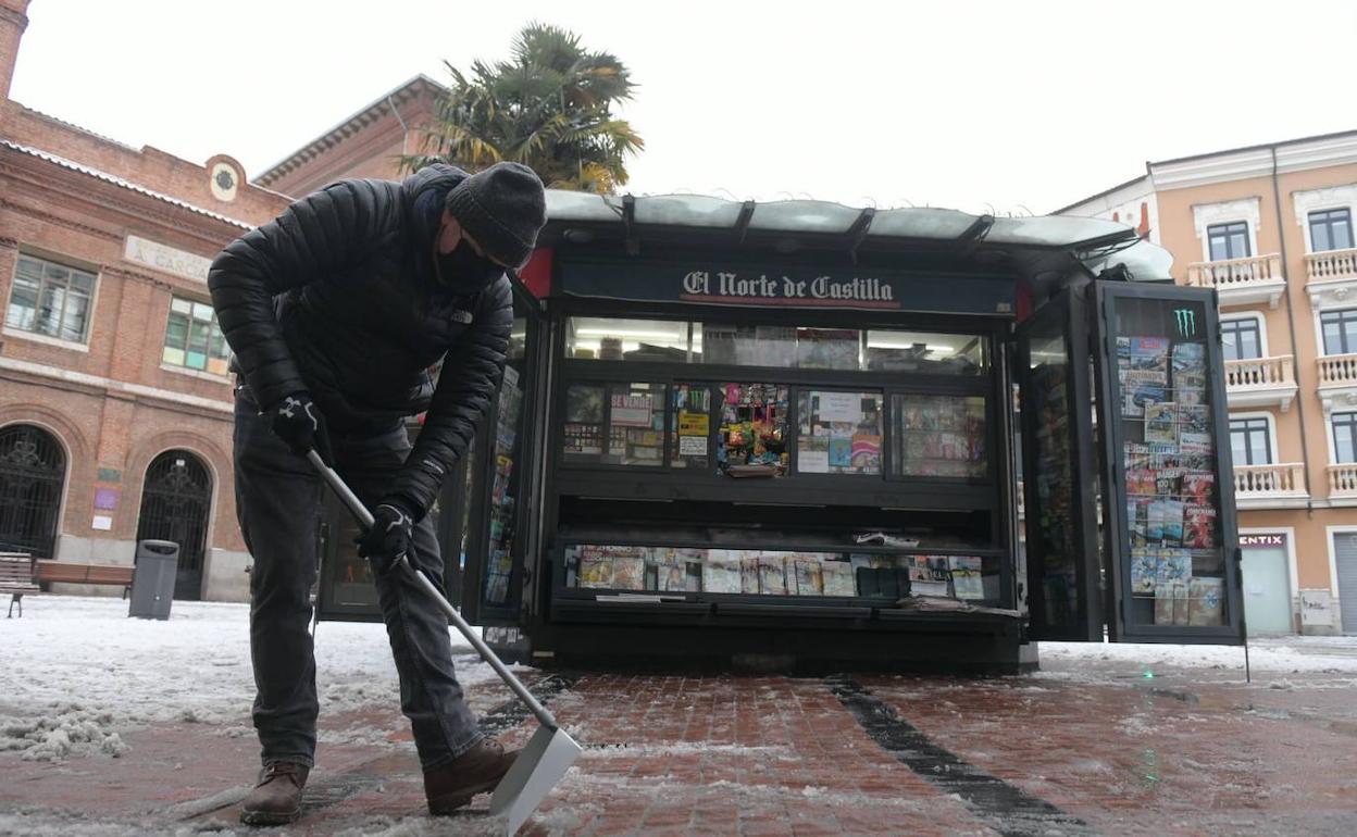 Un hombre retira el hielo en la plaza de España, frente a un quiosco abierto. 