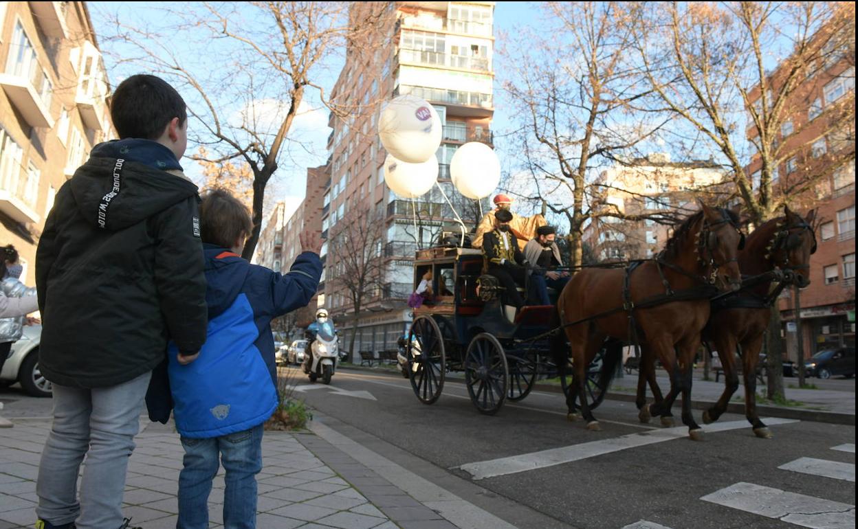 Dos niños saludan el paso de la cabalgata de Reyes en Valladolid capital. 