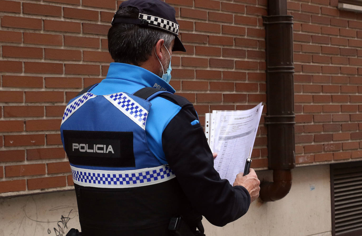 Un policía local comprueba la lista de seguimientos de control de la cuarentena.
